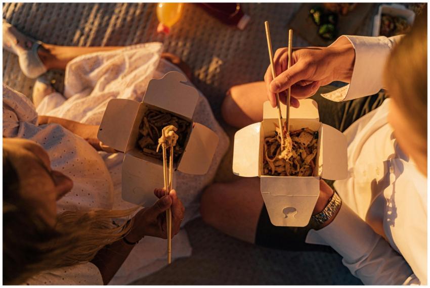Two people enjoy takeout noodles during a relaxed