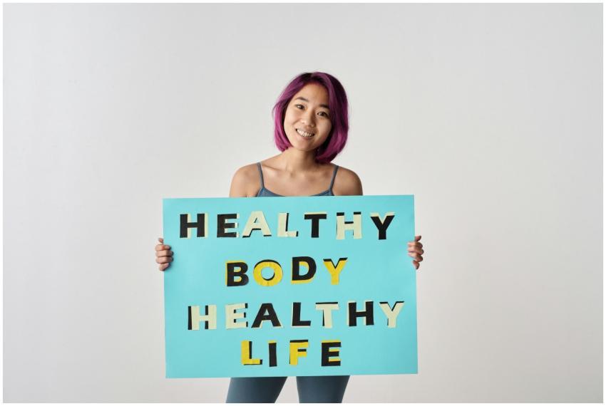 A young woman with purple hair holding a poster pr