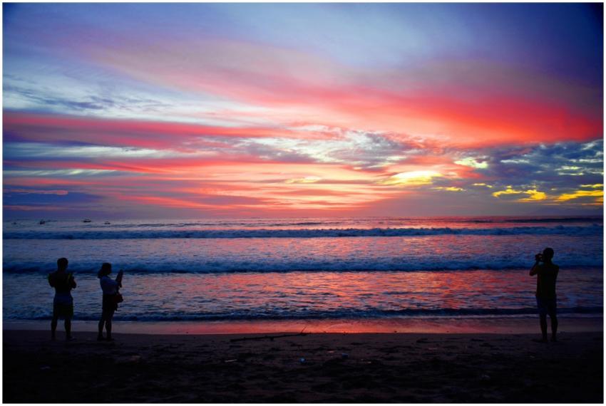 Silhouetted people capturing a stunning sunset ove