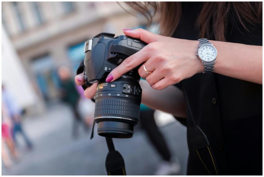 A woman adjusting a DSLR camera outdoors, focusing