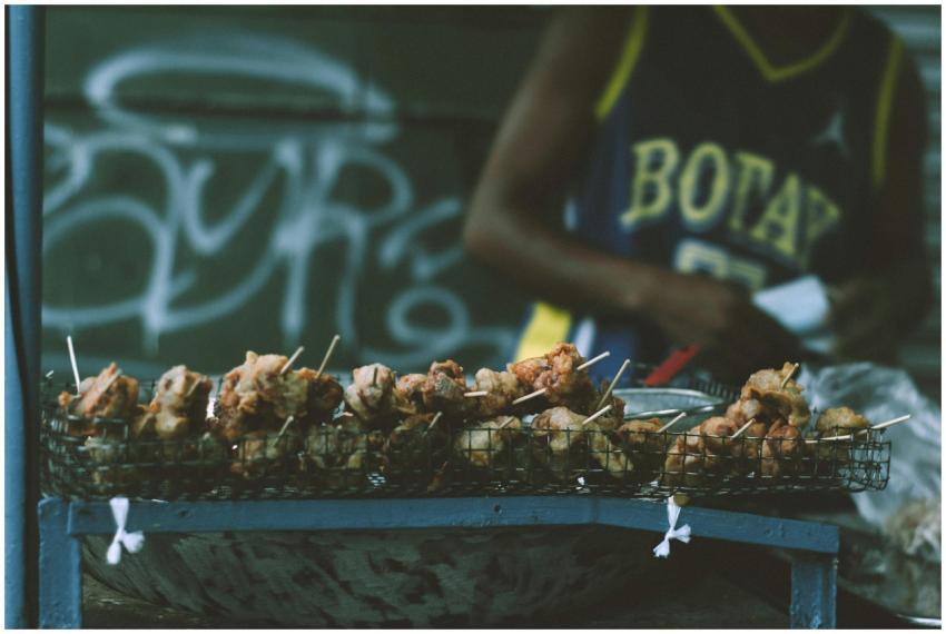 Street vendor preparing grilled skewers at an outd