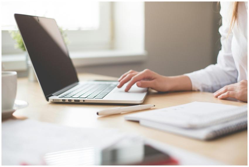 A businesswoman typing on a laptop at a bright ind