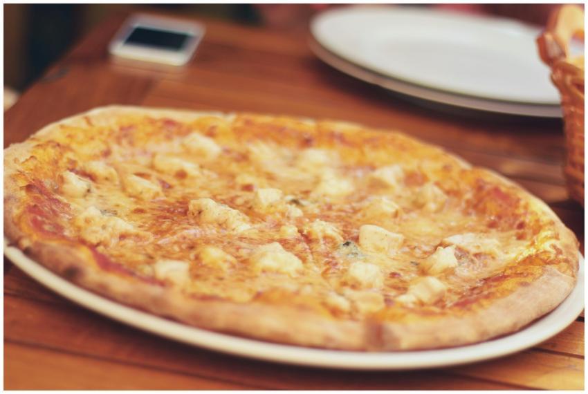 Close-up of a cheese pizza on a wooden table, read