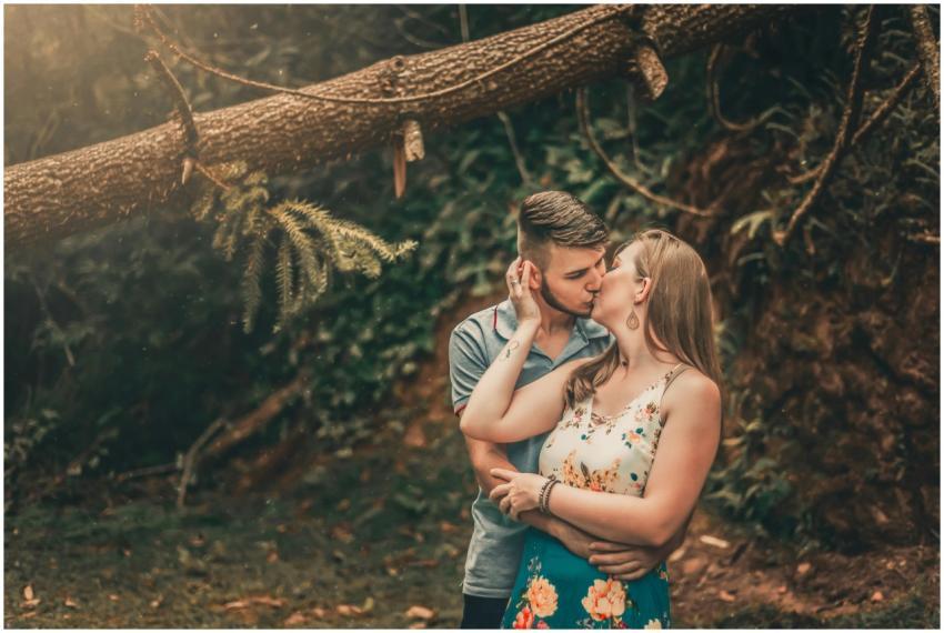 A couple shares a romantic kiss surrounded by lush