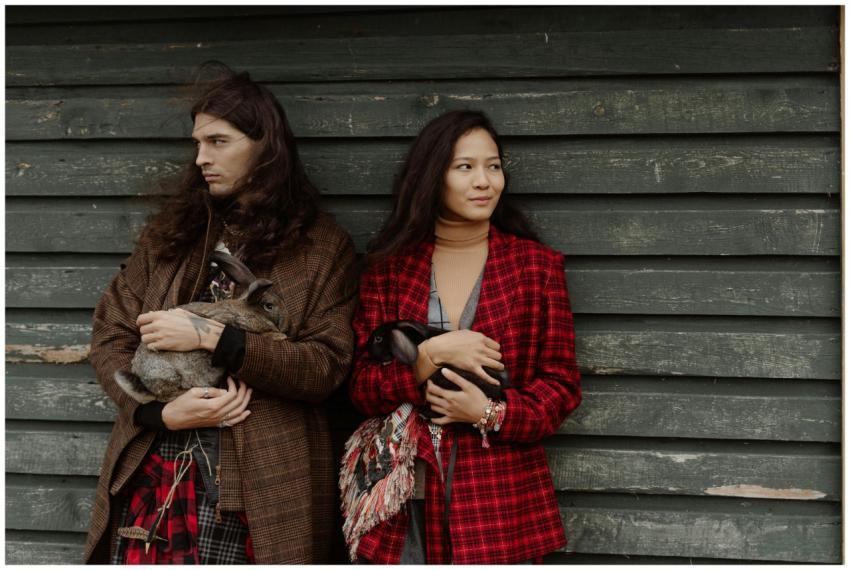 A stylish couple in bohemian attire holds rabbits