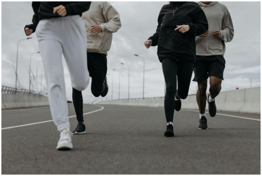 Four people jogging together on an urban road, sho
