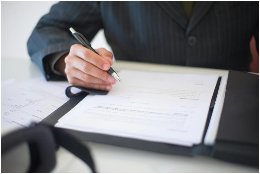 Close-up of a hand signing documents with a pen, s