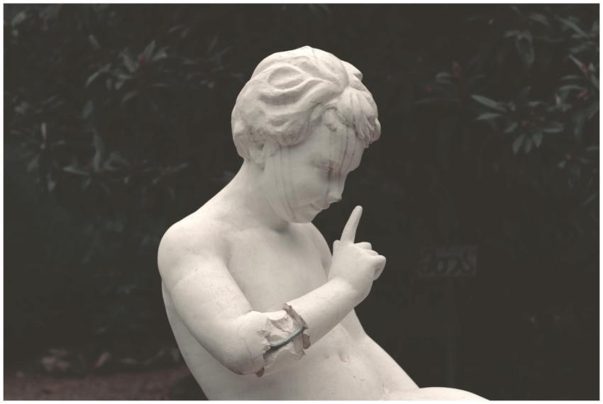 A classical marble statue of a child in a gesture