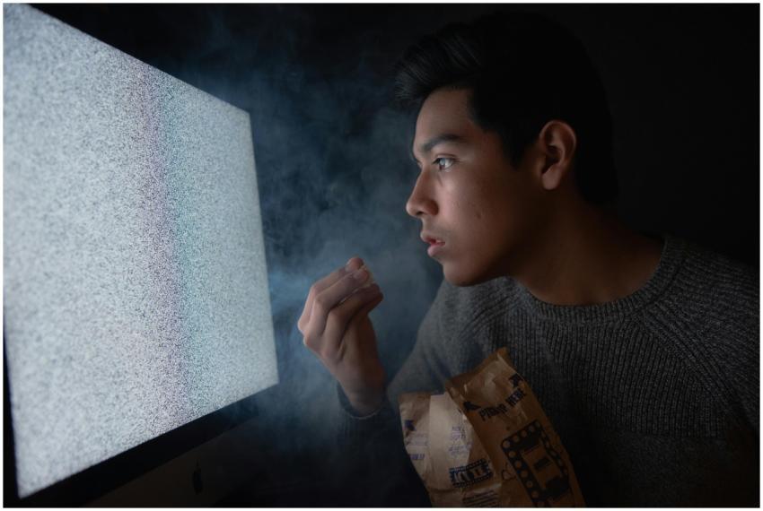 A young man engaged in watching TV static with pop