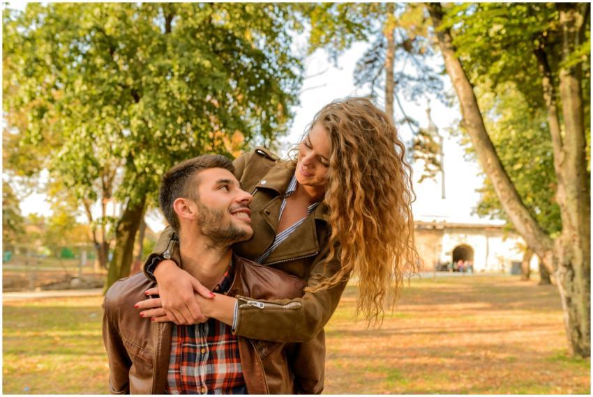 Smiling couple embracing in a sunlit park during f