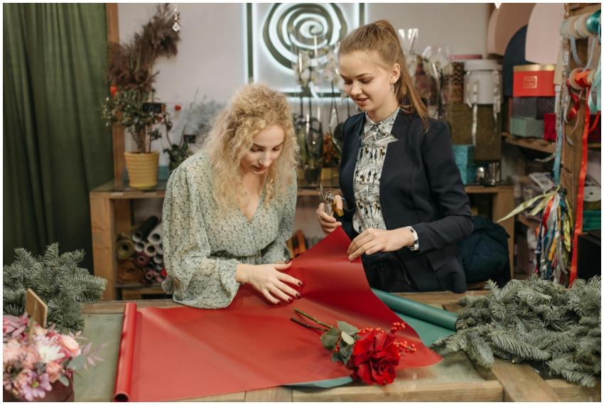 Two women wrapping gifts with red paper in a cozy