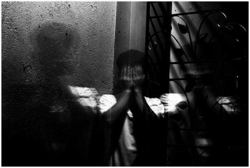 Grayscale image of a man covering his face, evokin