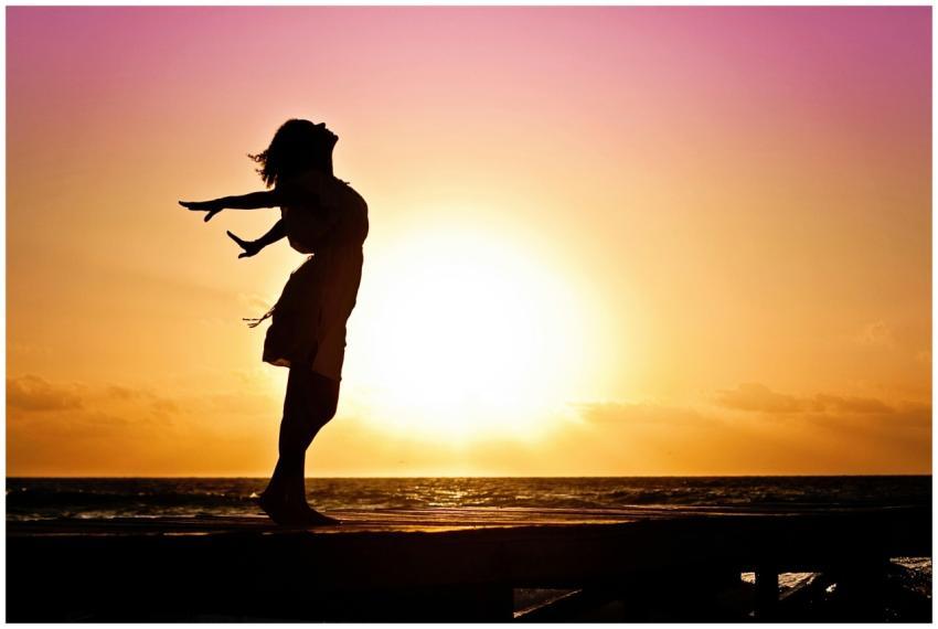 Silhouette of a woman at the beach with arms outst