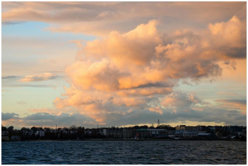 Golden sunset clouds over a city skyline reflected