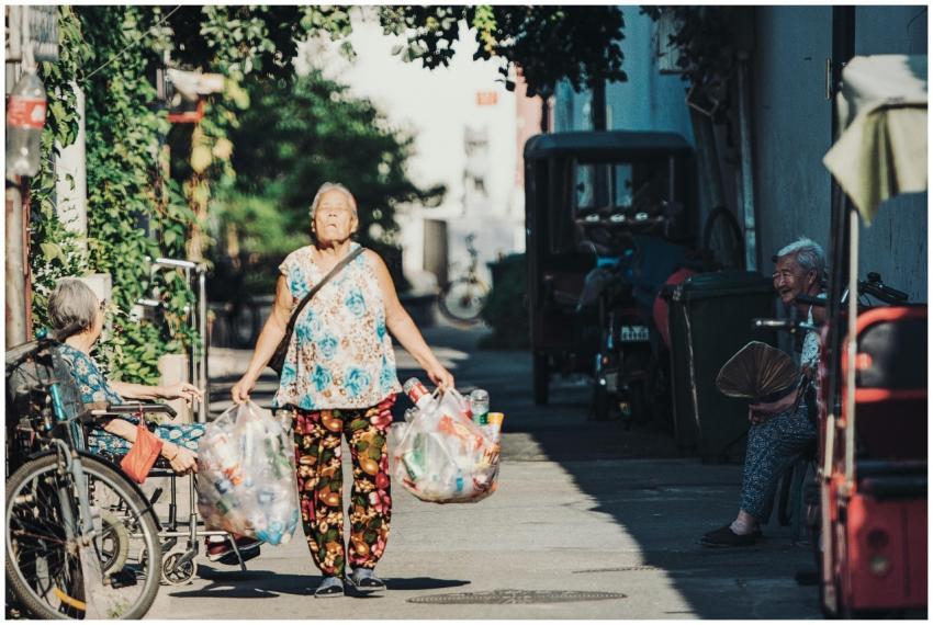 An elderly East Asian woman walks through a Beijin