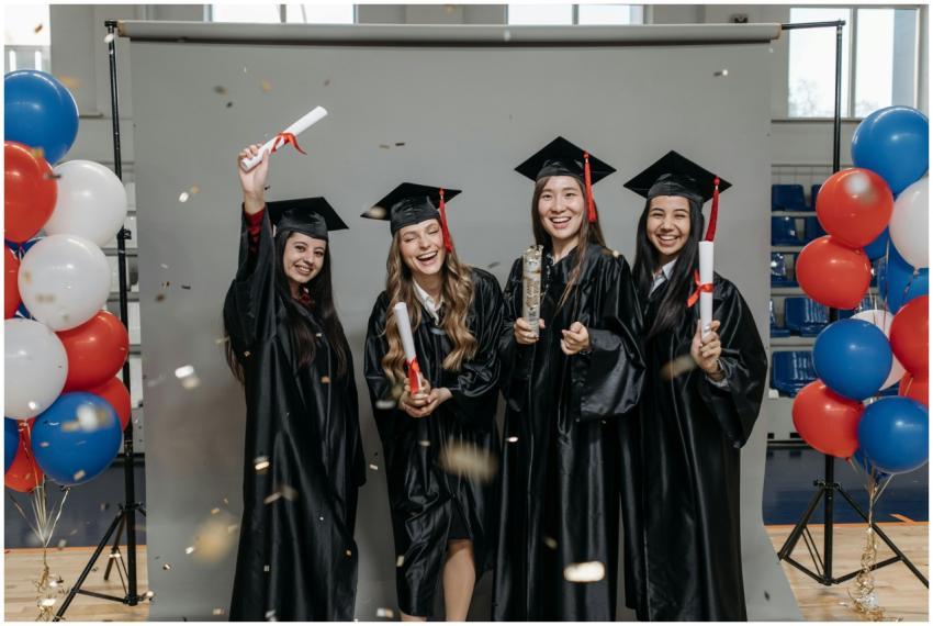 Four young female graduates celebrate indoors with