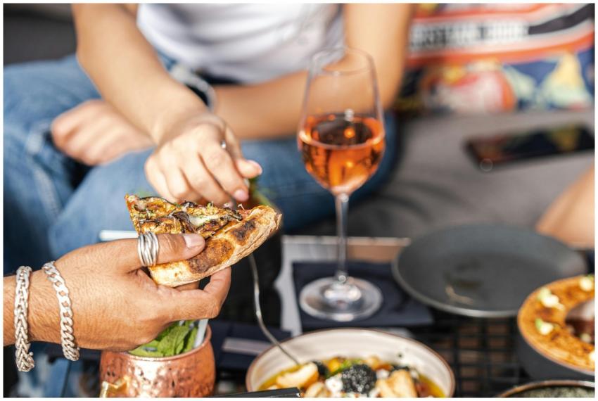 Friends enjoying pizza and rose wine at an indoor
