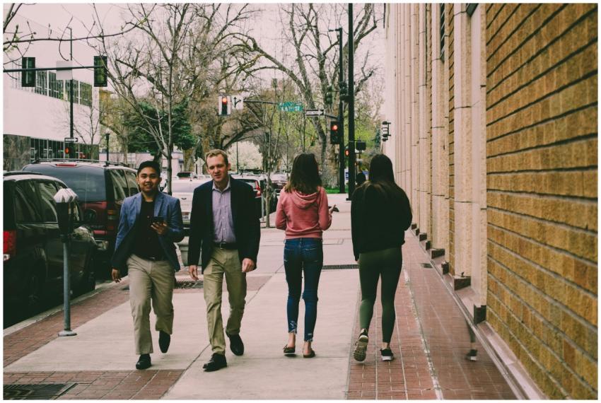 Four adults walking on a city sidewalk during the