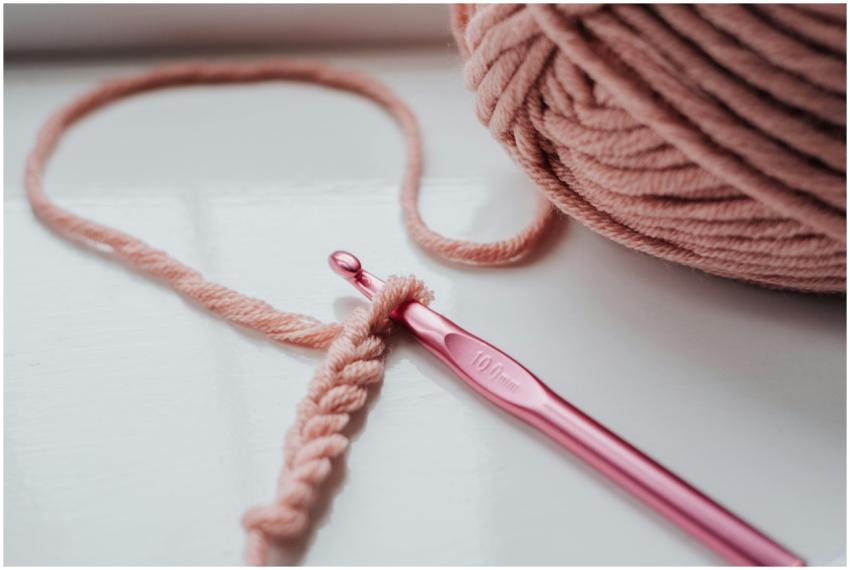 Close-up of pink yarn and crochet hook on a bright
