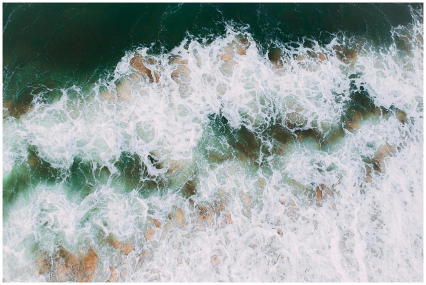 A stunning aerial shot of ocean waves crashing ont