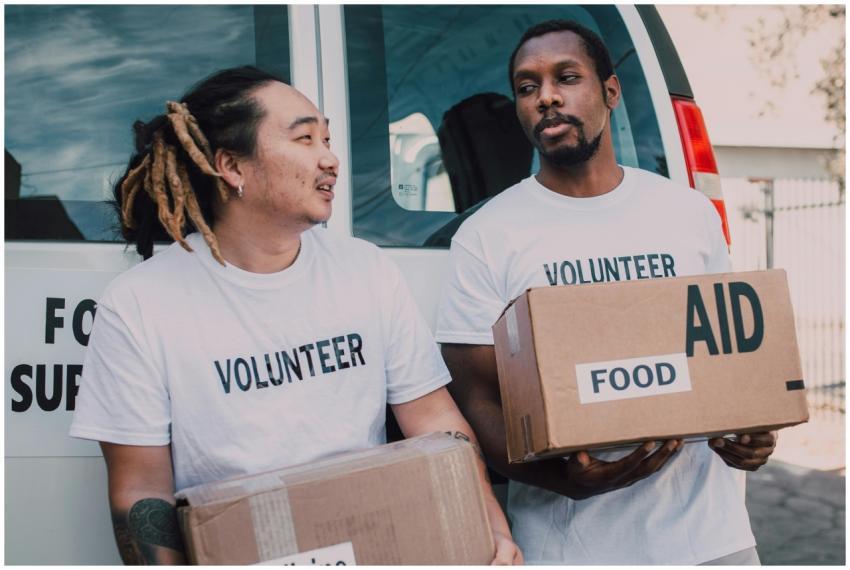 Two volunteers wearing white shirts distribute foo