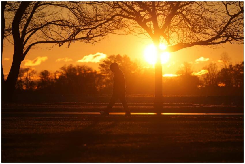 A person walks along a path during a vibrant sunse