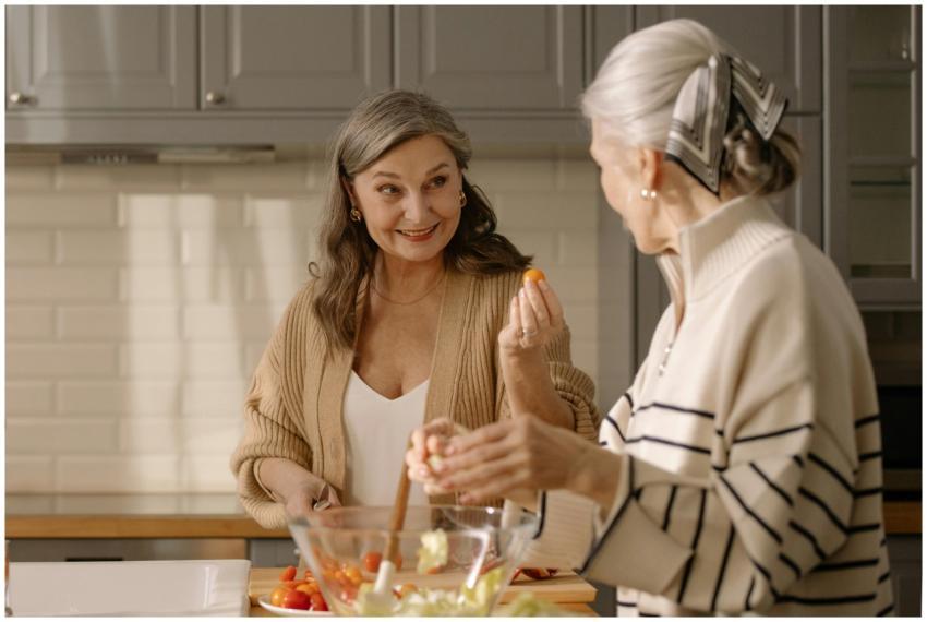 Two senior women smiling and preparing a fresh sal