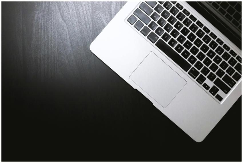 Top view of a sleek laptop on a dark wooden desk,
