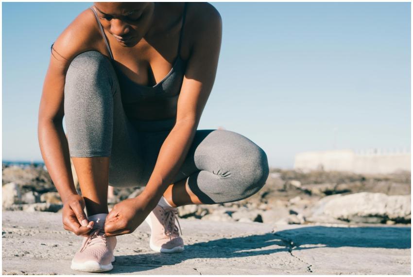 A woman in activewear tying her sneakers outdoors,
