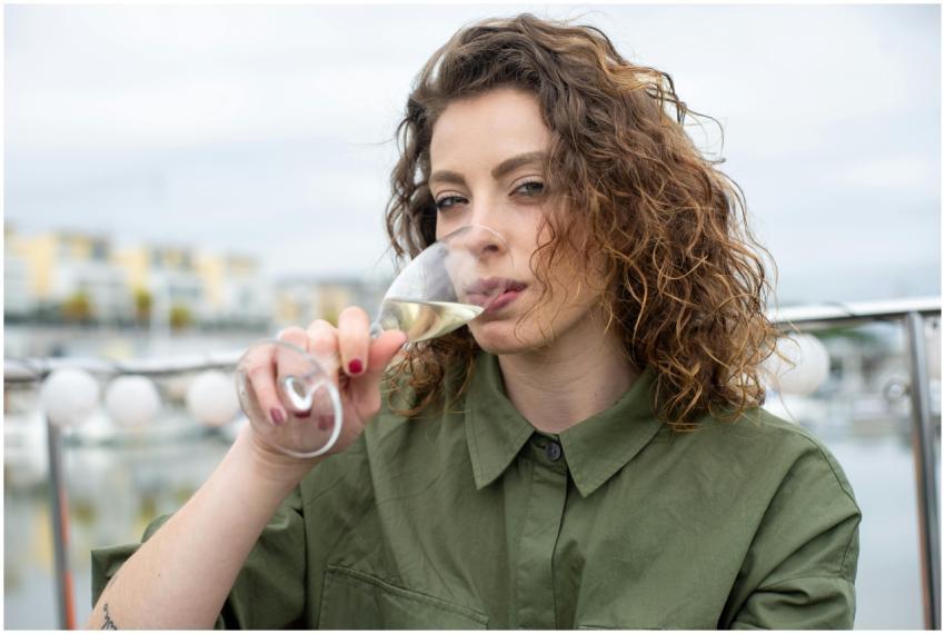 A woman in a green shirt enjoying a glass of wine