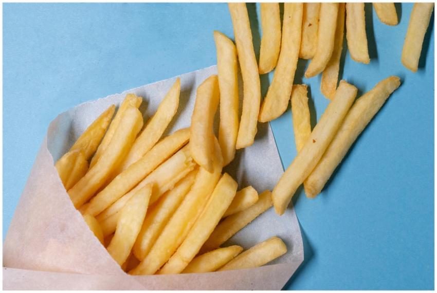 Top view of tasty french fries in paper placed on