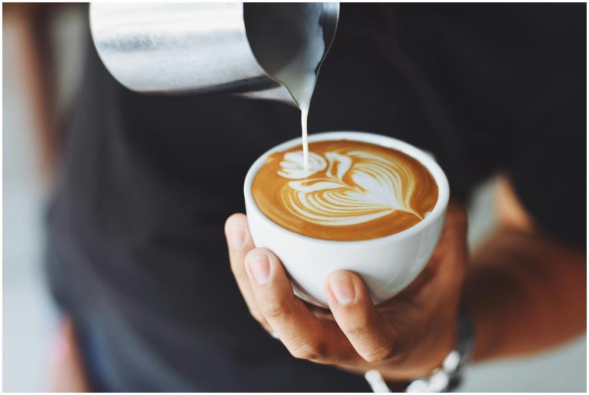 Close-up of a barista pouring milk to create latte