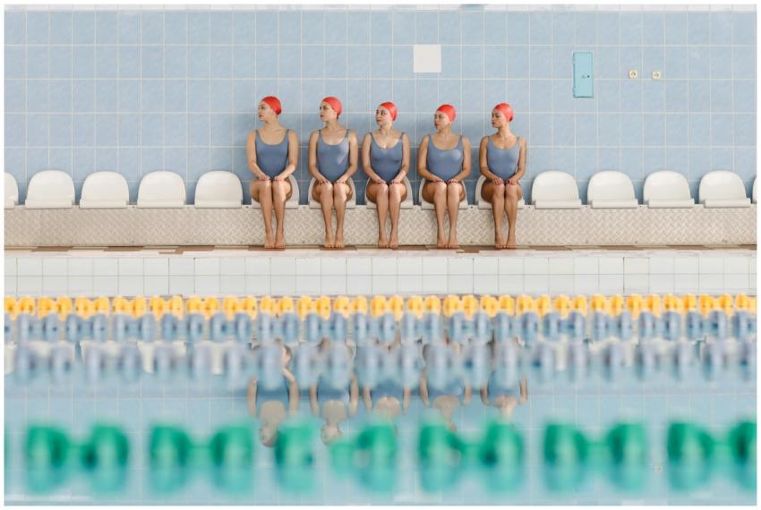 Synchronized swimming team members sitting poolsid