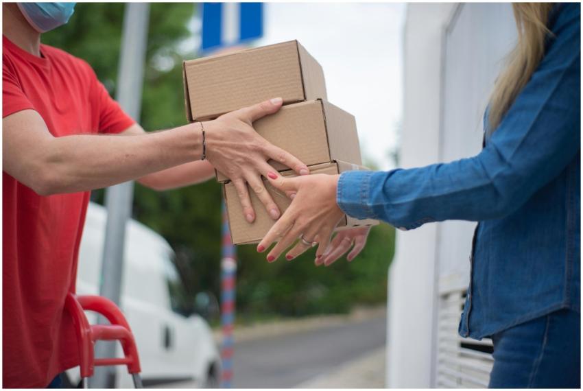 Hands exchanging cardboard boxes during an outdoor