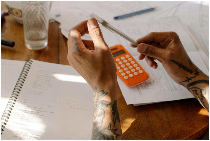 Close-up of tattooed hands holding a pen next to a