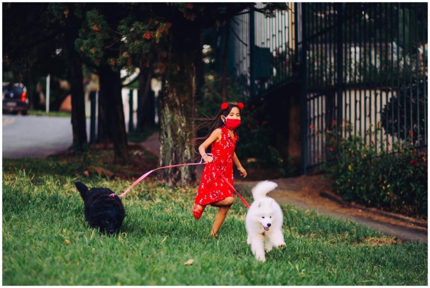 A young girl in a red dress and face mask joyfully