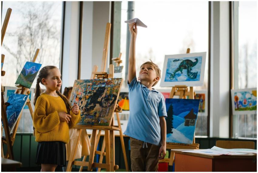 Kids enjoying paper planes amidst colorful paintin