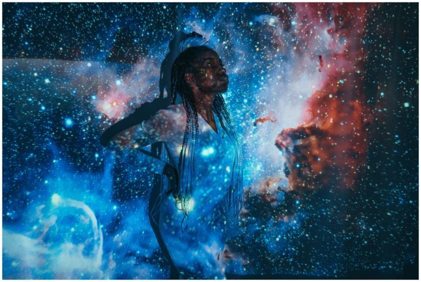 A woman with braided hair poses, surrounded by a c