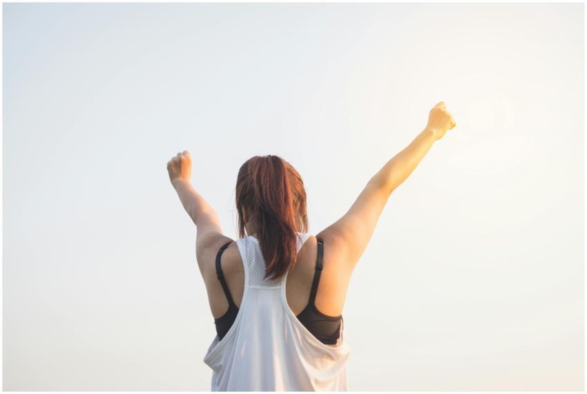 A woman celebrates success with arms raised in a b