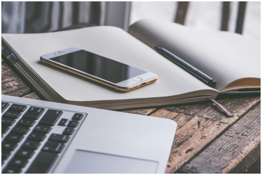 Open notebook with a smartphone and laptop on a wo