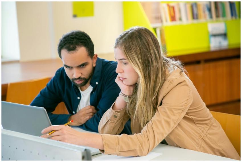 Concentrated multiracial classmates using laptop f