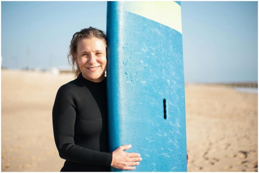 Senior woman smiling while holding surfboard on a