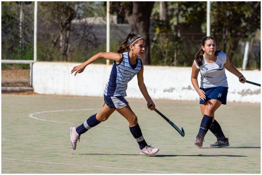 Girls playing an intense game of field hockey on a