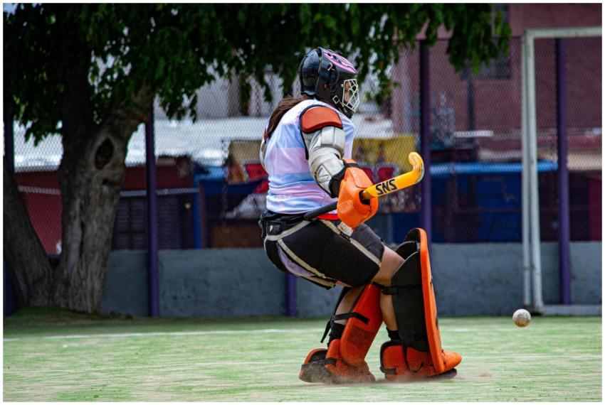 A field hockey goalie in full gear saves a shot du
