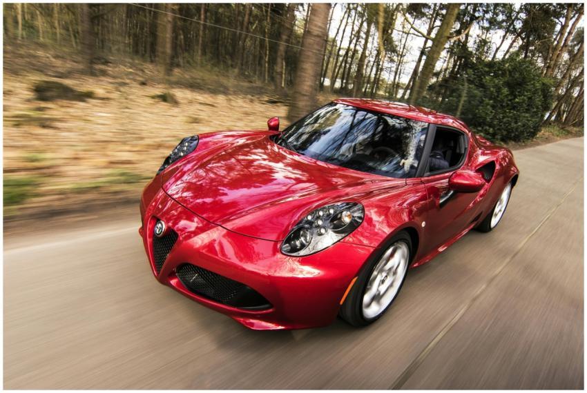 A sleek red sports car driving fast on a forest ro