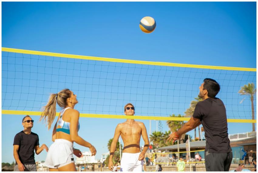 Four people actively play volleyball on a sunny be