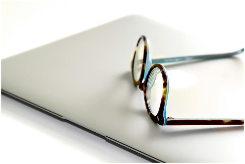 Close-up of eyeglasses on a sleek, modern laptop,