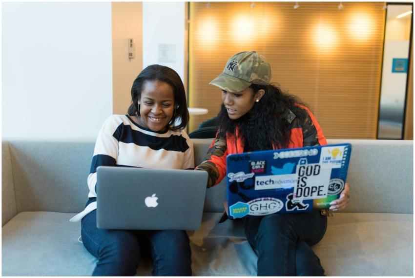 Two women pair programming on laptops, sharing ide