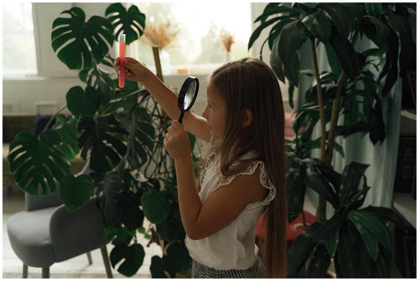 A young girl examines plants with a magnifying gla