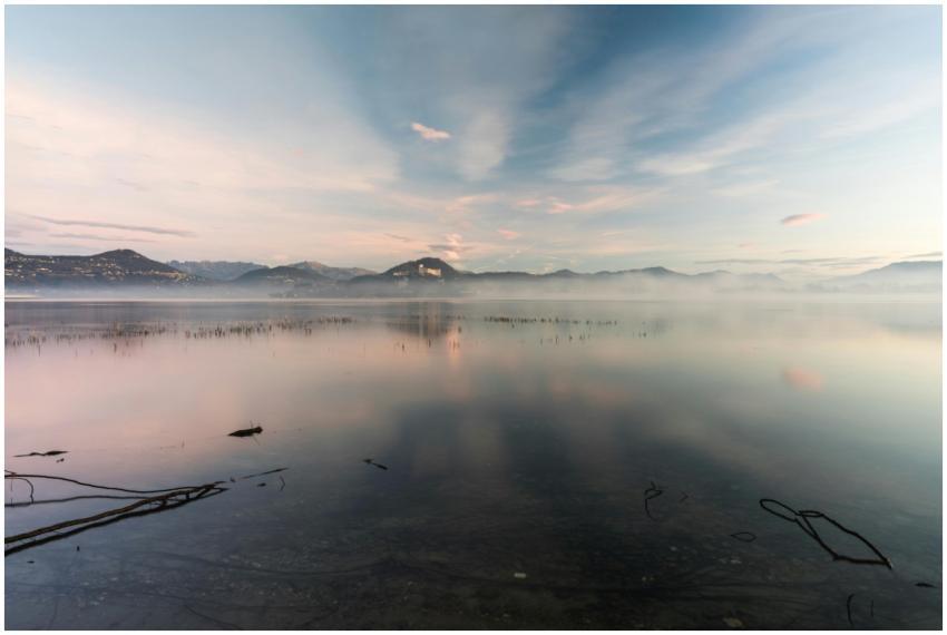 Tranquil misty lake at sunrise with mountain refle